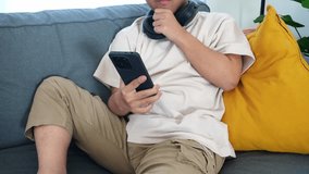 Excited young man with Down Syndrome thinking while scrolling smartphone at home - Powered by Shutterstock - Get 15% off with code: PIKWIZARD15