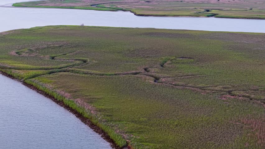 Aerial drone view of a winding river and grassy banks in Charleston, South Carolina, capturing curves of the waterway and surrounding marsh landscape.