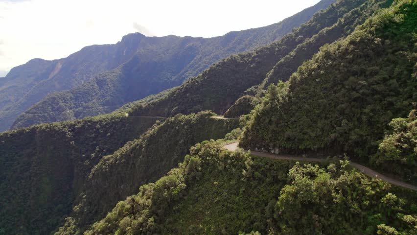 Stunning drone footage capturing the perilous, unpaved North Yungas Road in Bolivia, famous as the. The video highlights the narrow path and the steep, lush mountainsides of the Yungas region.