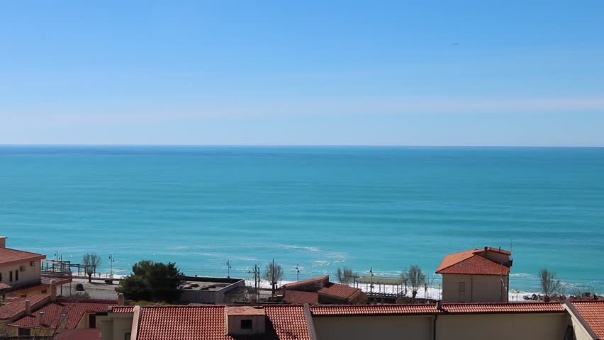 Ocean View From a Hill Station in Italy With Red-Roofed Houses and Clear Blue Sky