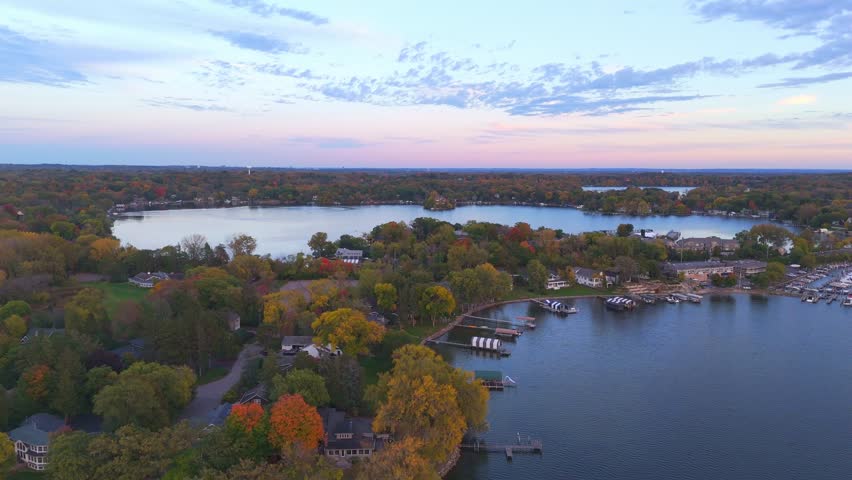 Aerial view of Excelsior shows homes nestled among vivid autumn trees, resting beside the peaceful waters of Lake Minnetonka.