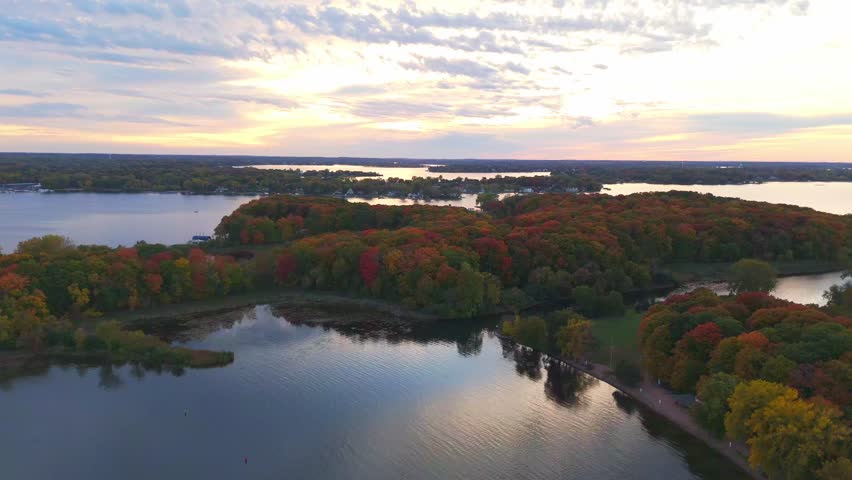 The fall landscape of Lake Minnetonka unfolds from above, with trees in full autumn hues surrounding the lake.
