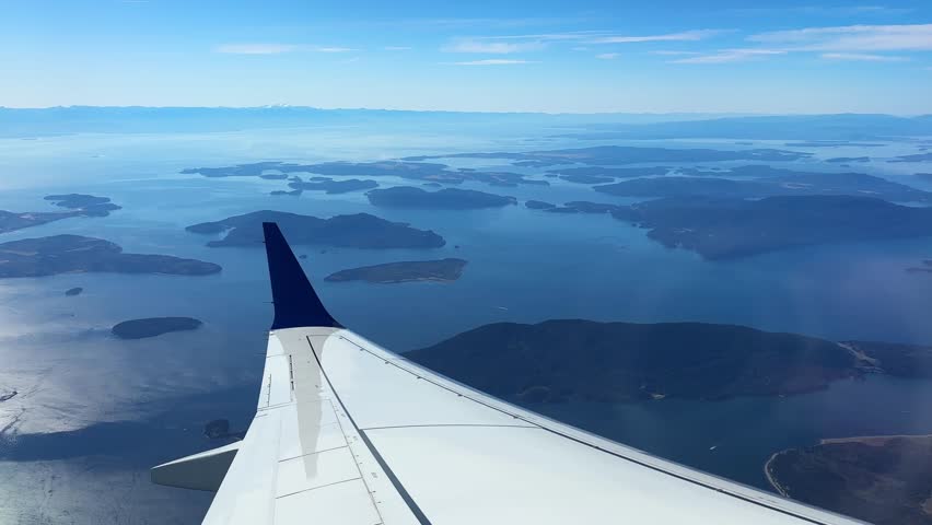 Airplane window POV shot flying over the San Juan Islands above the Salish Sea in British Columbia, Canada. 4K