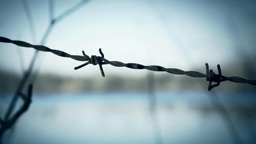 MS, Barbed wire fence surrounding prison, guard tower in background, Barrier from strangers people, refugees, prisoners. heavy duty chain-link fence