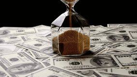 Sand dropping through the bulb of the hourglass and money on the background. Hourglass with sand stand among money. Deadline, business planning, finance and time is money concept. - Powered by Shutterstock - Get 15% off with code: PIKWIZARD15