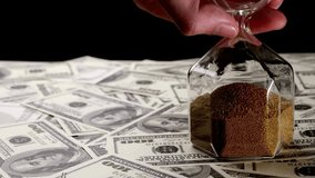 Sand dropping through the bulb of the hourglass and money on the background. Hourglass with sand stand among money. Deadline, business planning, finance and time is money concept. - Powered by Shutterstock - Get 15% off with code: PIKWIZARD15