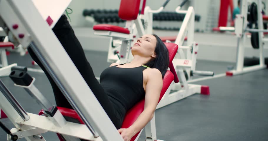 Gym workout. Slow motion 4k footage of a woman performs leg presses, engaging her legs with steady form and focused effort during her workout.