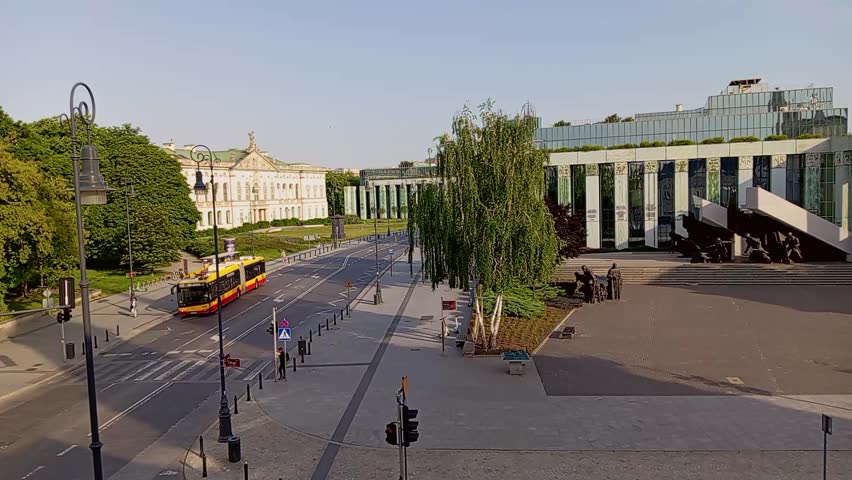 Street scene in Warsaw Old Town on May 28, 2025, featuring a tram passing by and pedestrians walking. Captures authentic European urban life, public transport and historic city atmosphere.