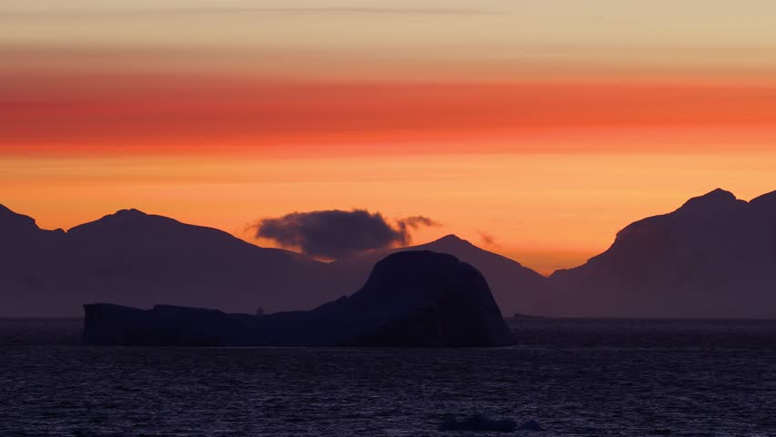 Antarctic Sunset with Vibrant Orange and Purple Sky over Mountains