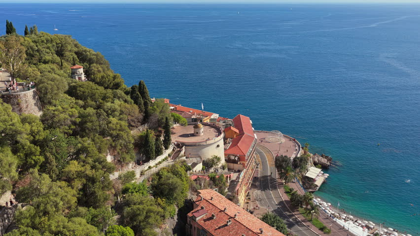 Aerial drone view of Castle Hill in Nice with its fortress walls, curved road, and panoramic view over the Mediterranean coastline
