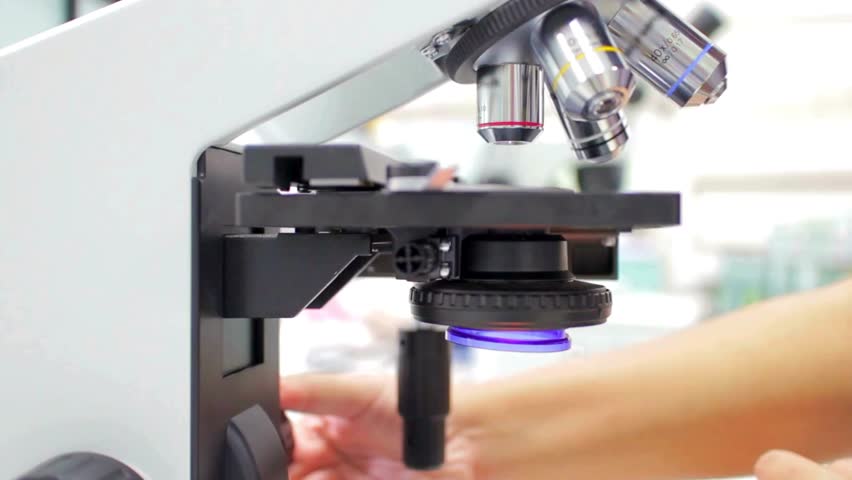 A chemist analyzes crystal formations under a microscope, researching materials for new applications in the electronics and high tech industries.