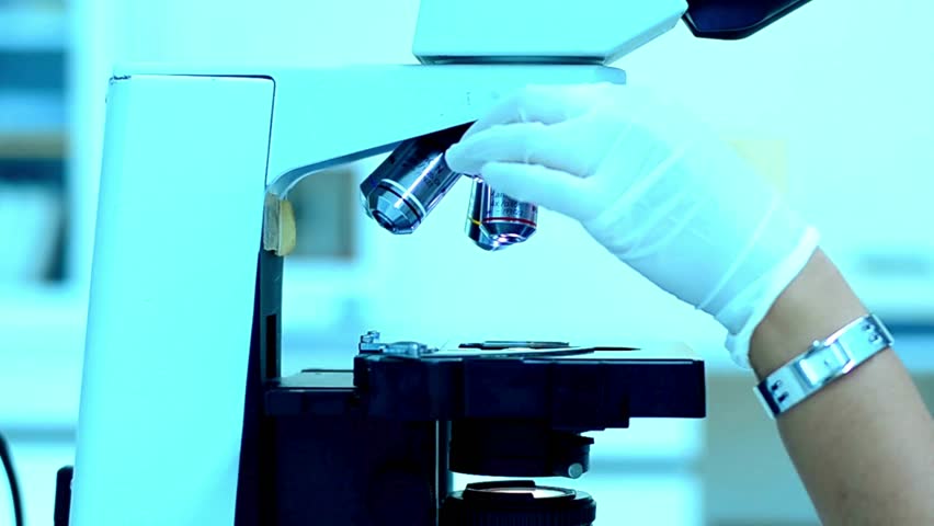 A chemist analyzes crystal formations under a microscope, researching materials for new applications in the electronics and high tech industries.