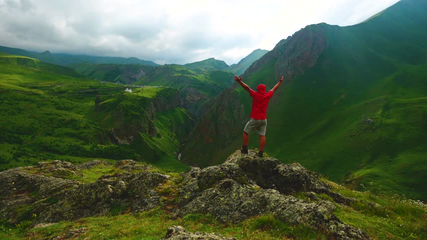 a backpacker in the mountains on top of a peak looks down at a gorge