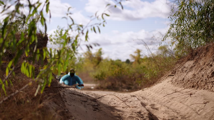 ATV riders on sandy trail kick up dust while powering through sunlit scrubland, low angle shots emphasize speed and rugged terrain, loose sand, tire tracks.