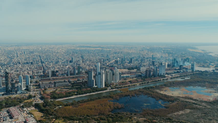 Wide aerial drone view of Buenos Aires skyline with dense urban buildings and the Rio de la Plata in the background.