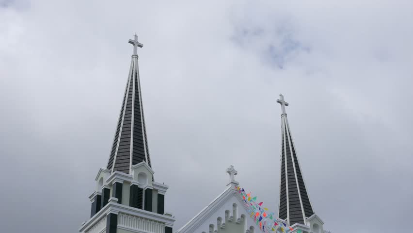 Clouds move across the sky in a timelapse view above a Catholic church tower, revealing the steady presence of sacred architecture against accelerated atmospheric change. Spiritual heritage.