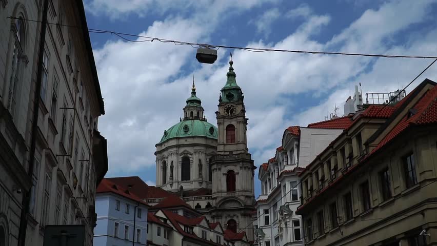 Street view in Prague looking up at baroque church dome and tower under clouds