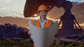 Asian Female Engineer With Safety Helmet Looking At Blueprint In Her Hands While Standing With Large Satellite Dish - Powered by Shutterstock - Get 15% off with code: PIKWIZARD15