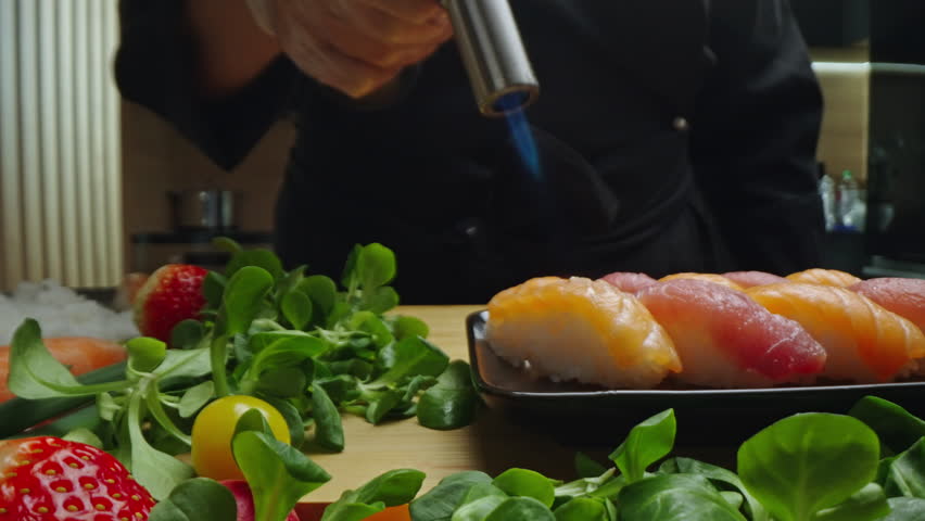 Chef searing fresh sushi with a culinary torch for enhanced flavor and texture