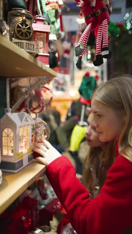 Mother and child looking at Christmas decorations at a Christmas market in Europe, night walk at Christmas in a European town, winter holidays with a family