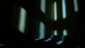 A shadow of an old jail cell door, casting on the wall of a small prison cell while opening, with a bit of a rug on the floor. a 4K video clip. - Powered by Shutterstock - Get 15% off with code: PIKWIZARD15