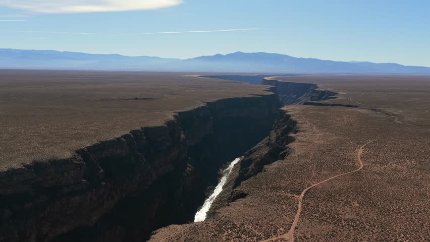 Dramatic vertical view from high above the Rio Grande Gorge, revealing the deep river canyon and the exposed rock cliff walls of the chasm in the American Southwest.