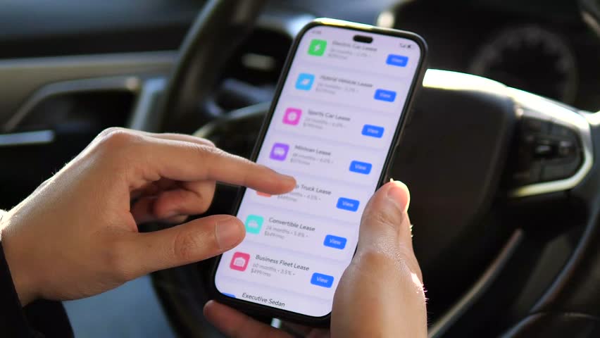 The hesitation before a major financial commitment. This shot captures a driver thoughtfully tapping his phone while reviewing various leasing proposals, embodying the universal moment of weighing
