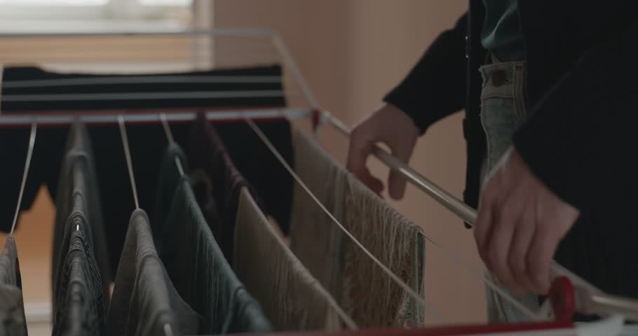 Young Man Hangs Laundry on the Dryer. 4K 10-bit