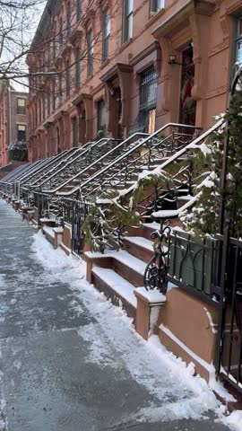 Walking down a snowy historic, brownstone-lined street after a winter storm in Harlem, New York City