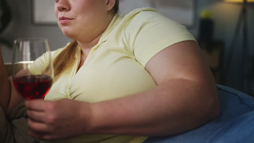 Young plus size woman drinking wine and telling secrets to friend, relaxation
