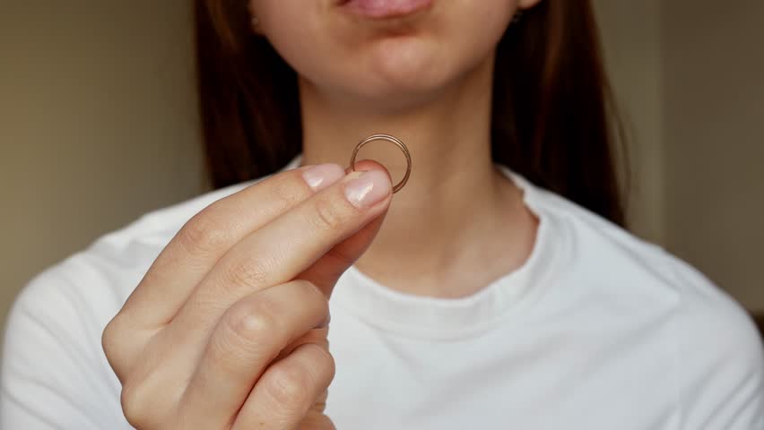 Close-up of a woman's hand with a wedding ring. A broken heart, divorce, and a painful farewell.