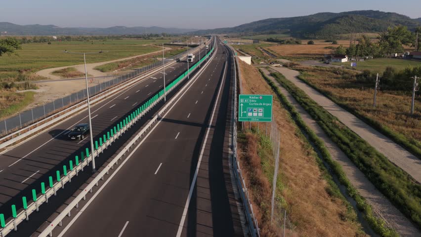 A1 highway from Bucharest to Pitesit Curtea de Arges and Sibiu 4K video. Newly built A1 Highway in Romania, cutting through rural fields and valleys, with mountains visible in the distance.