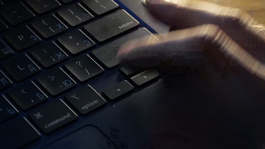 Extreme close up of a person's finger repeatedly and rapidly pressing the arrow keys on a laptop keyboard in a dark room, conveying a sense of stress, anxiety, or urgent navigation during a high