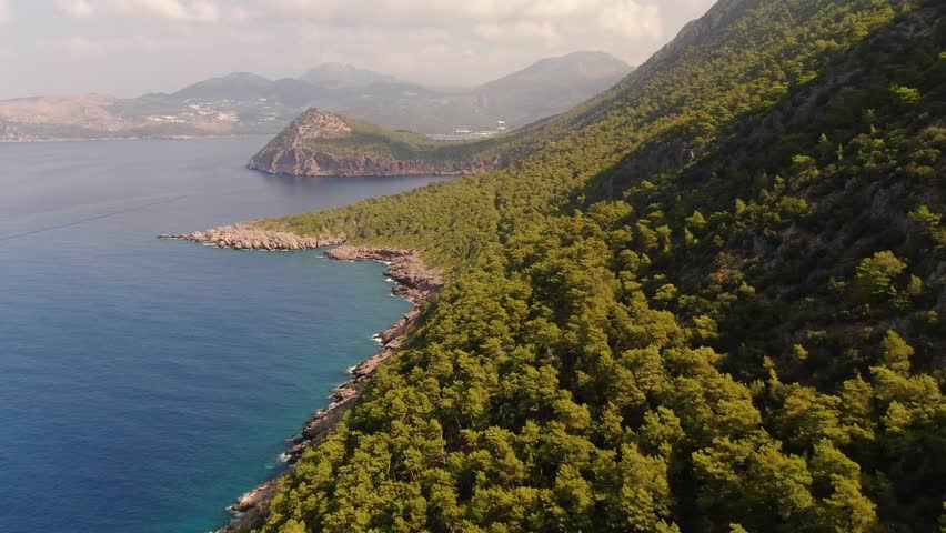A breathtaking coastal landscape along the Mediterranean coast, where lush green forests and rocky mountains meet the turquoise sea.	
