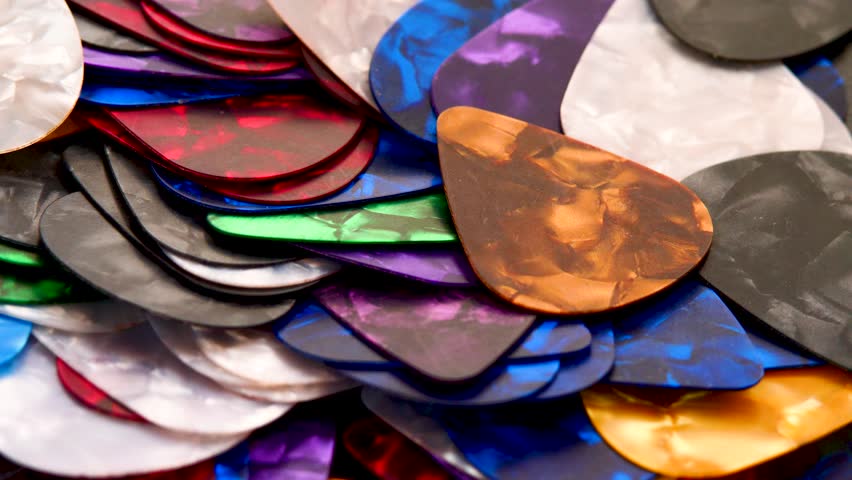 Close up rotating colorful guitar picks captured in smooth motion, creating vibrant and playful atmosphere. ideal for, advertising visuals, instrument promotions, energetic video intros