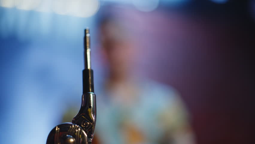 Metal drum rod standing closeup during music setup on club stage. Male musician adjusting hardware at blurred concert space. Professional preparing to play percussion musical instrument at nightclub.