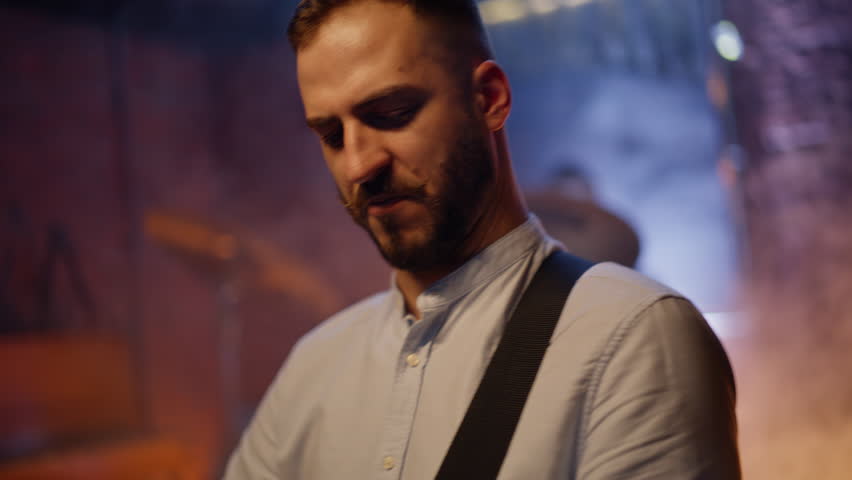 Talented man playing guitar at scene nightclub closeup. Enthusiastic guitarist performing music at acoustic instrument enjoying concert with rock band in modern bar stage. Professional musician show.