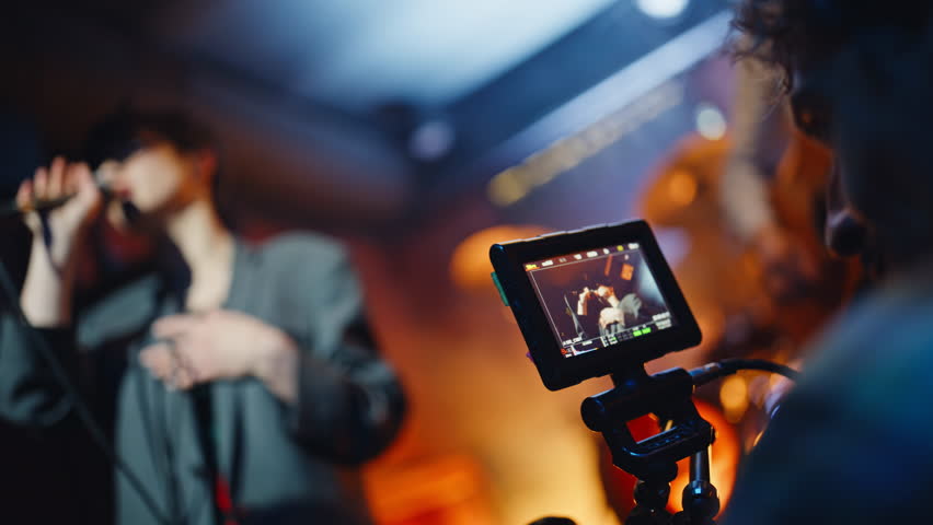 Musical band performing in bar stage recorded by professional videographer closeup. Trendy woman singing in microphone on nightclub scene. Talented cameraman filming live performance in night club.