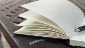Open blank notebook and pen with pages gently moving with the breeze. Handheld camera.  - Powered by Shutterstock - Get 15% off with code: PIKWIZARD15