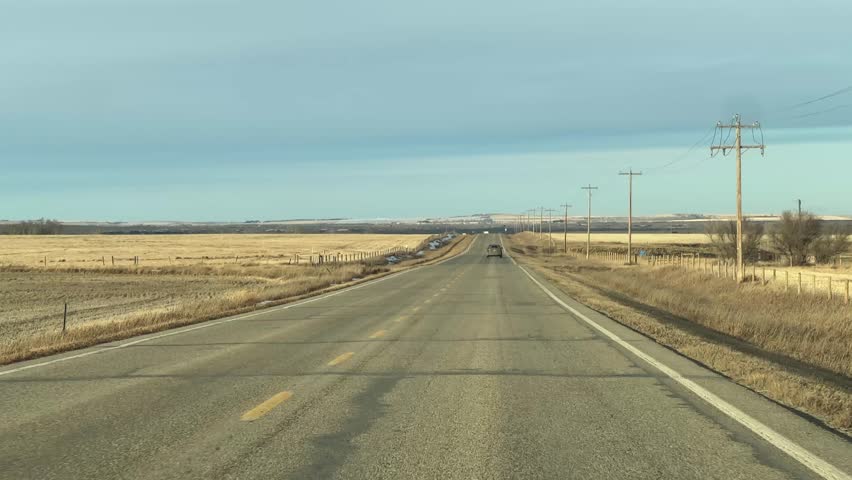 Mild Winter highway travel through open prairie under clear skies