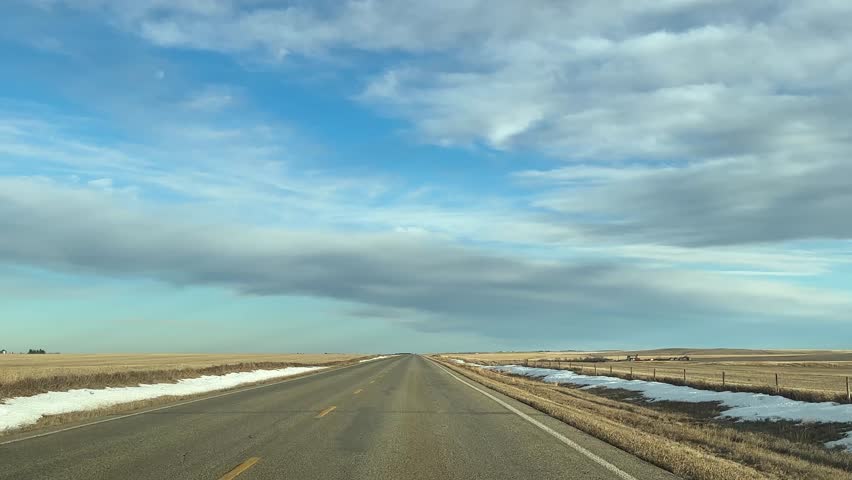 Mild Winter highway travel through open prairie under clear skies