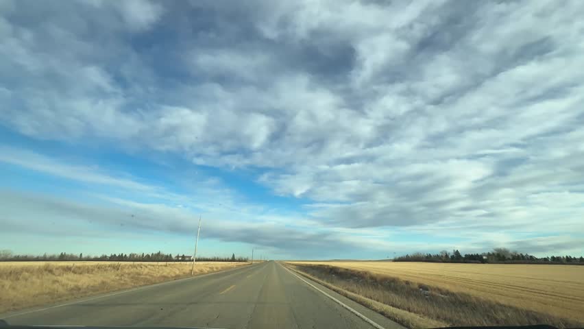 Mild Winter highway travel through open prairie under clear skies