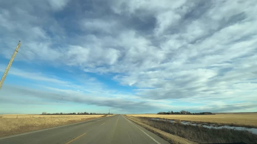 Mild Winter highway travel through open prairie under clear skies
