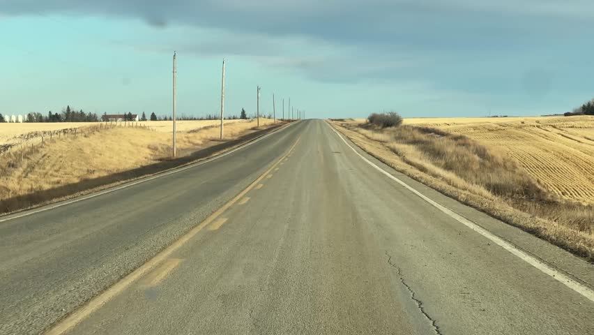 Mild Winter highway travel through open prairie under clear skies