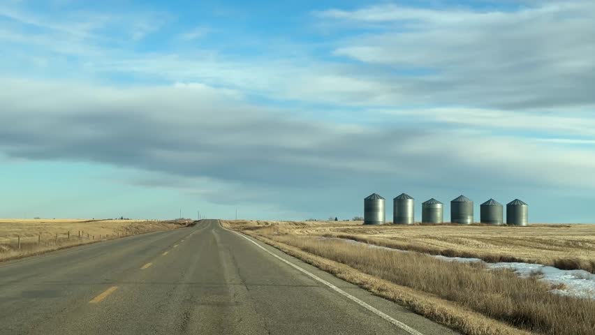 Mild Winter highway travel through open prairie under clear skies