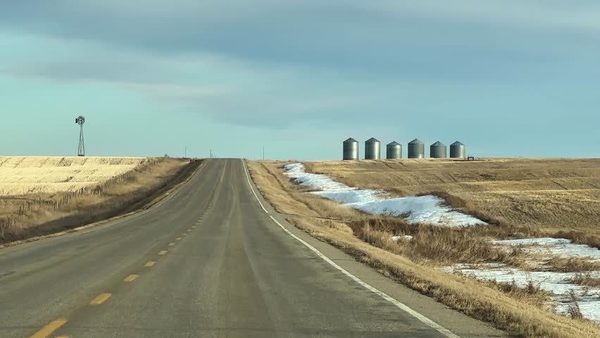 Mild Winter highway travel through open prairie under clear skies