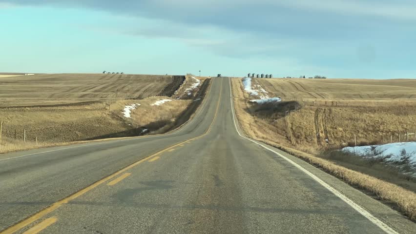 Mild Winter highway travel through open prairie under clear skies