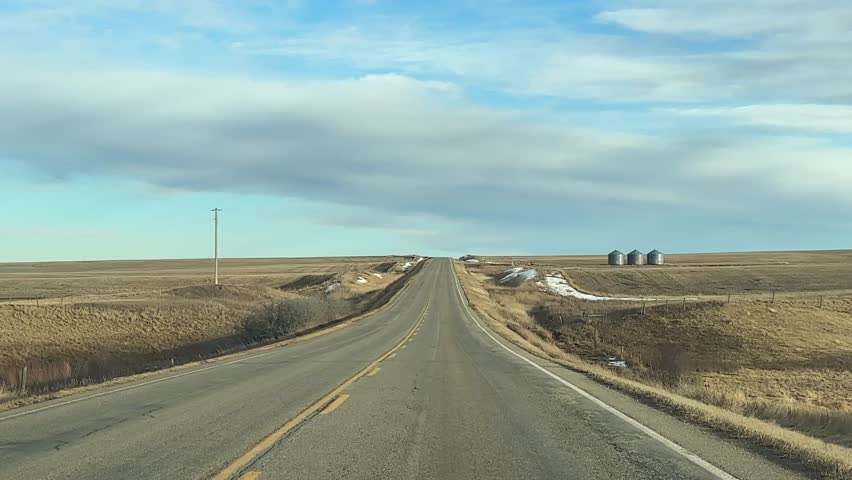 Mild Winter highway travel through open prairie under clear skies