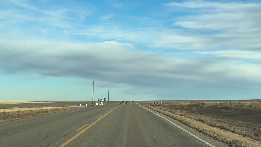 Mild Winter highway travel through open prairie under clear skies
