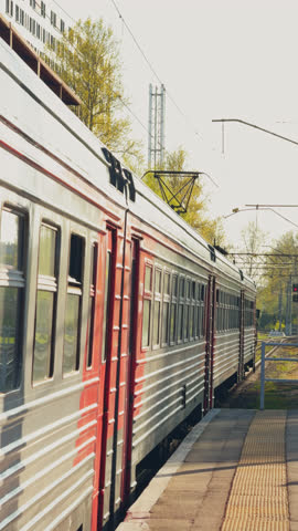 Russia, St.Petersburg, the electric train stops at the railway station, The passenger electric train goes nearby summer park, train of the Russian Railway company